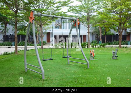 children colorful playground with plastic swing on green grass in the park Stock Photo