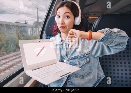 The girl is dissatisfied and disappointed with the bad signal of Wi Fi Internet in public transport train Stock Photo