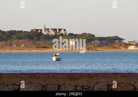 Man fishing from a small motor boat in the bay of Santander with the Magdalena Palace in the distance Pedreña Cantabria Spain Stock Photo