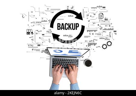 Data backup for data recovery to original or new location. The person is working on a laptop. Stock Photo