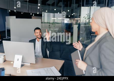 Two multiracial coworkers talking during working day in office Stock Photo