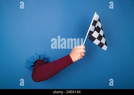 hand holding checkered flag over blue background Stock Photo