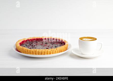 Homemade berry pie with cherry and cup of coffee cappuccino  on white wooden table. Copyspace. Stock Photo