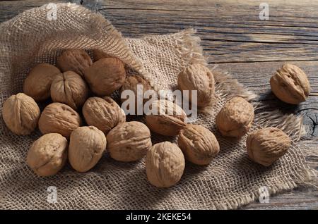 Whole walnuts on burlap located on a rustic wooden table close-up Stock Photo