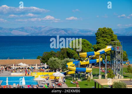 Moraitika, Greece - 09 22 2022: View on Ionian Sea and Greece Balkan Peninsula, People Sunbathe And Relax Beside Pool With Waterslides in Hotel Stock Photo
