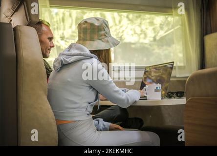 Father and His Daughter Playing on a Laptop Inside Their Camper Van. RV Family Vacation Theme. Stock Photo