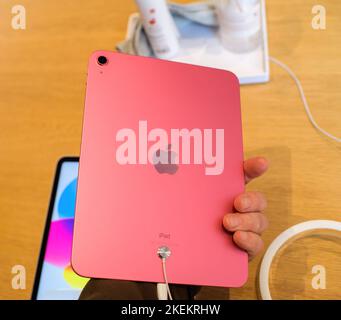 Paris, France - Oct 28, 2022: Male hand close-up of new Apple Computers iPad 10th generation in Pink color in store - looking at the rear camera with big logotype insignia on the back Stock Photo