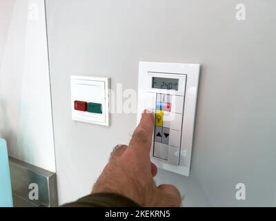 Man setting temeperature in hospital room on the wall switcher Stock Photo