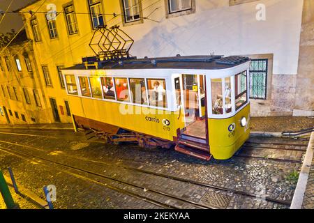 Lisbon, Portugal - December 29, 2008: Traditional yellow tram downtown Lisbon by night in Lisbon, Portugal. In 1901 the first electrical streetcar too Stock Photo