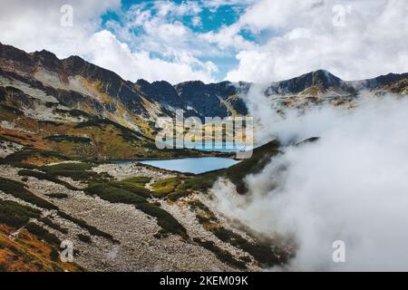 Two clear mountain lakes with reflection in the middle of Tatra national park five lake valley surrounded by pines, mountains and fog in Poland