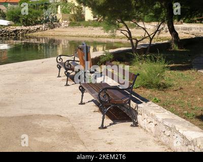 Empty benches at the seashore on the island of Veli Iz in Croatia. Stock Photo