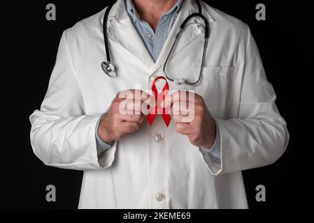 Doctor holds a red ribbon with both hands, symbol of World AIDS Day. Support from health personnel to people with hiv. Prevention and fight against th Stock Photo