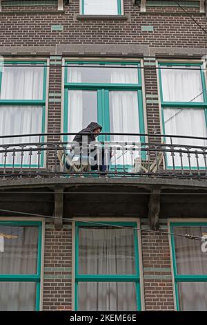 amsterdam, noord-holland/netherlands - 2022-11-03: amstelstraat - a man sitting on a balcony watching his mobile phone  --   [credit: joachim affeldt Stock Photo