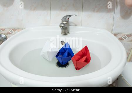 Children's paper boats float in the sink in the bathroom at home Stock Photo