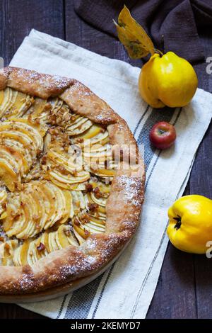 Open pie stuffed with apples, quince and nuts on a wooden background. Rustic style. Stock Photo