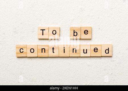 To be continued word written on wood block. To be continued text on cement table for your desing, concept. Stock Photo