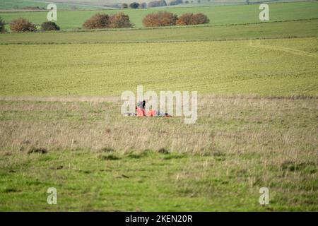 A parachutist gathering the parachute having landed in a grass meadow Stock Photo