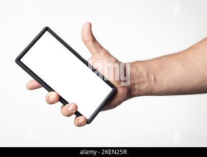 Hand and arm of a man holding a cell phone with a blank screen on a nuclear white background. Stock Photo