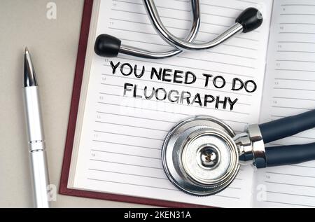 Medicine concept. On the table is a stethoscope, a pen and a notebook in which it is written - You need to do fluography Stock Photo