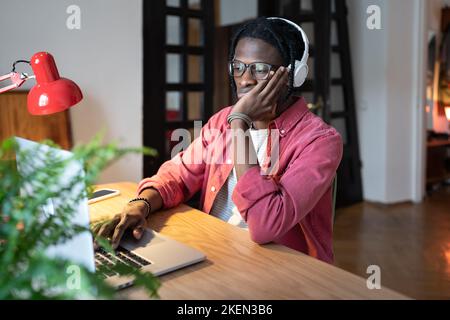Concentrated puzzled African American man procrastination or doing monotonous work at laptop Stock Photo