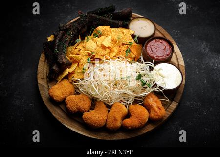 Snacks with sauce, for beer on a wooden board, on a dark background Stock Photo