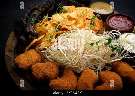 Snacks with sauce, for beer on a wooden board, on a dark background Stock Photo