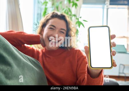 Happy young woman holding mobile phone in hand showing cellphone mockup screen. Stock Photo