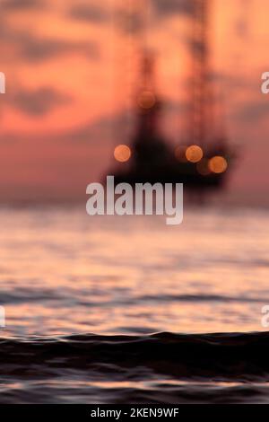 Silhouette of an offshore oil rig at sunset in the South China Sea Stock Photo