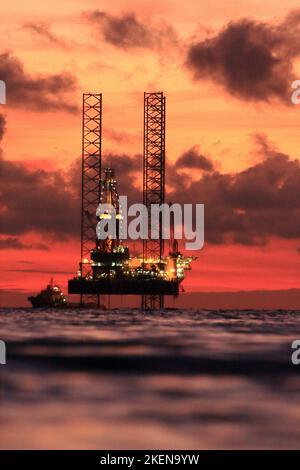 Silhouette of an offshore oil rig at sunset in the South China Sea Stock Photo