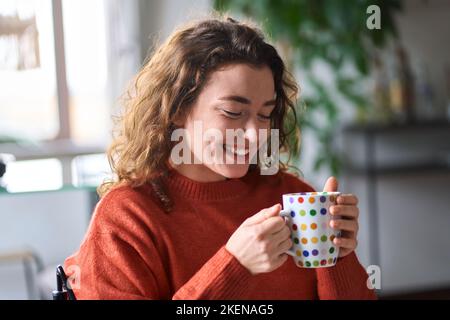 Young happy pretty woman drinking tea or coffee relaxing at home. Stock Photo