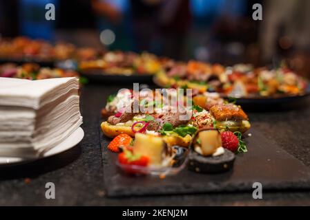 Set of beautiful canapes on black stone plates. Buffet table. Catering. Stock Photo
