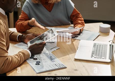 Close-up of two business partners using tablet pc and planning financial project in team at meeting Stock Photo