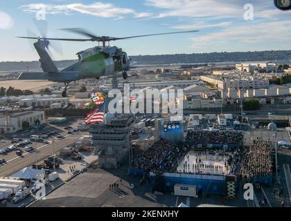 221111-N-EV253-1235 SAN DIEGO (Nov. 11, 2022) – An MH-60S Knighthawk, assigned to the 'Merlins' of Helicopter Sea Combat Squadron (HSC) 3, participates in a commemorative flyover of the Nimitz-class aircraft carrier USS Abraham Lincoln (CVN 72) during the Armed Forces Classic, Carrier Edition 2022. During the event, which was held on Veteran's Day, a basketball court was constructed on Lincoln's flight deck, and the Gonzaga Bulldogs played against the Michigan State Spartans. HSC-3 is the Navy's West Coast MH-60S fleet replacement squadron, responsible for training pilots and aircrewmen by pro Stock Photo