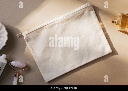 Blank canvas makeup bag mockup on a beige, cream background. Natural sunlight Stock Photo