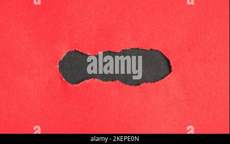 Torn red hole on black background. As template for message or advertisement. Stock Photo