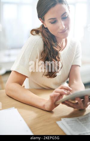 Tech savvy and successful. a young businesswoman using a digital tablet. Stock Photo