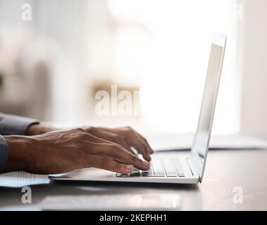 Closeup, hands and typing on laptop with black man at desk for email, communication or digital marketing in office. Zoom, businessman hand and Stock Photo