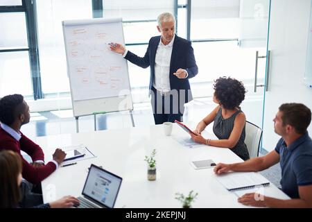 Highlighting the latest business statistics. a mature businessman giving a presentation in the boardroom. Stock Photo