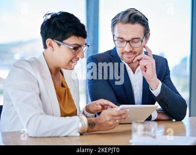 The possibilities for online inspiration are endless. two colleagues using a tablet together in an office. Stock Photo