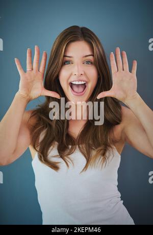 Ive got something amazing to tell you. Studio portrait of a confident young woman posing against a gray background. Stock Photo