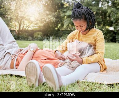Mother, picnic and happy child in a interracial family with a smile, floor hug and happiness. Summer fun, adoption and love of mom and girl on a Stock Photo