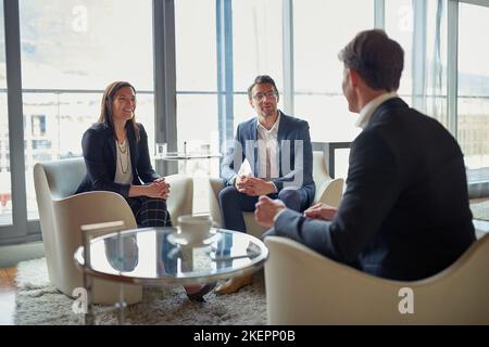 Their feedback is invaluable. three businesspeople talking in a corporate office. Stock Photo