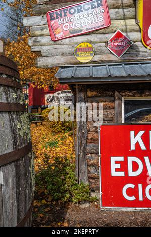 Vintage tin advertising signs on a log building in front of red caboose lodging at Black Bear Creek Antiques near Lake Burton in Clayton, Georgia. Stock Photo