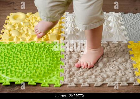 Baby toddler foots close-up on a medical orthopedic mat. Child legs with flat feet on a medical rug. Kid aged one year four months Stock Photo