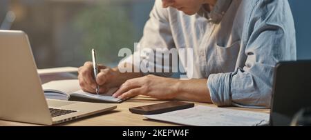 young entrepreneur taking notes in working at night. Stock Photo