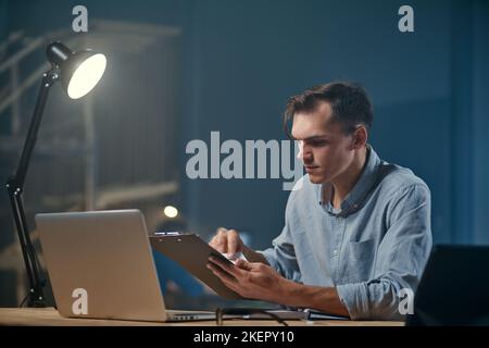 young businessman works with documents in a night office . Stock Photo