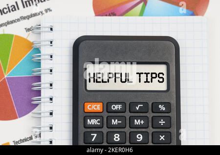 Business and economy concept. On the table are charts, a notebook and a calculator with the inscription - Helpful Tips Stock Photo