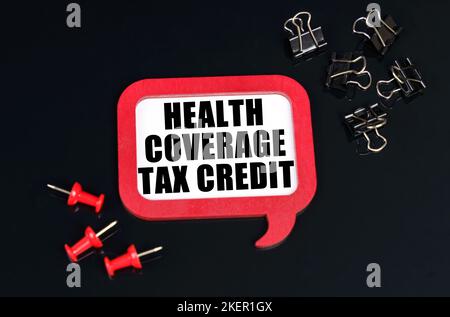 Economy and business concept. On a black surface, office supplies and a red plaque with the inscription - Health Coverage tax credit Stock Photo