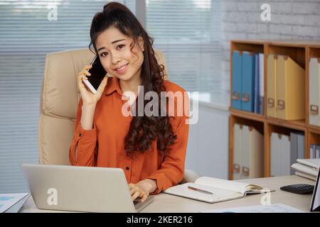 Portrait of young beautiful business woman calling on phone at her workplace Stock Photo