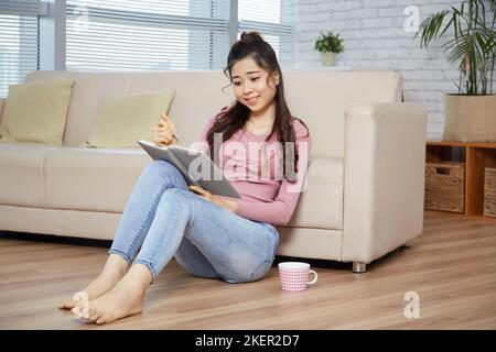 Pretty female student revising her notes in textbook Stock Photo